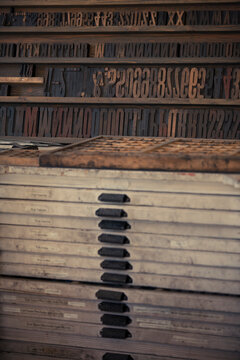 Antique wooden printing press boxes filled with large wooden letter and number plates.