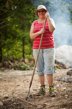 Portrait of a middle aged woman holding a garden rake.