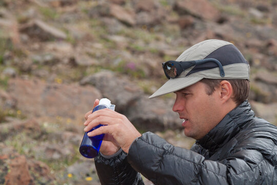 A backpacker measures rations fuel before lighting a stove during a multi-day backpacking trip.