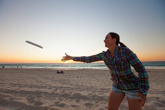 Young woman throwing plastic ring on beach, Perth, Western Australia, Australia