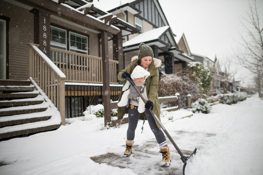 Mother with son shoveling snow in winter