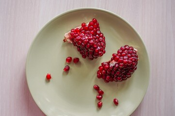 Bright red pomegranate Seeds on round green plate