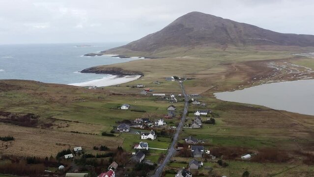 Drone shot of the village of Northton, featuring the surrounding seascape and a mountain in the background. Filmed on the Isle of Harris, part of the Outer Hebrides of Scotland.