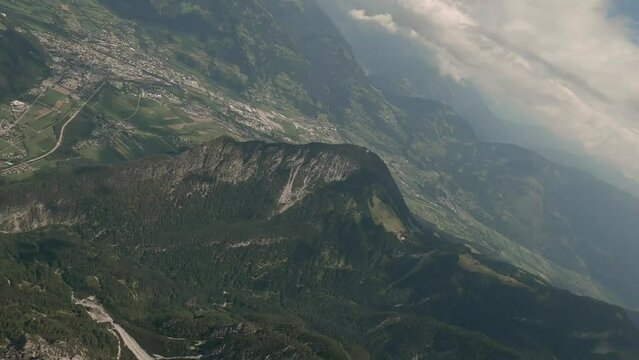 Action camera footage from FPV racing drone flying fast in clouds and  down a mountain in Austria in the summer. Spectacular views of the valley in the background. Drone is diving. LuPa Creative.