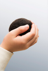 ヘアカットで出来た毛玉。男性の育毛、発毛ケア、増毛のイメージ。自分の髪の毛の玉を手に持つ男の子。