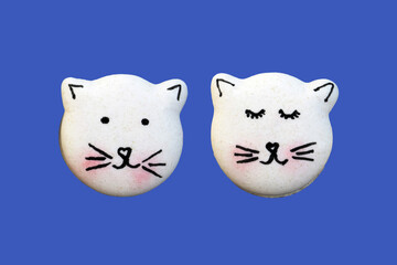 Cute macarons in a shape of cats isolated on blue background, top view. Creative baking