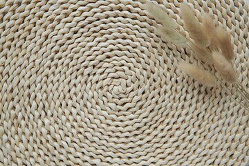 Natural, bohemian style background with wicker mat and dried bunny tail grass, close up view, space for product presentation or text.