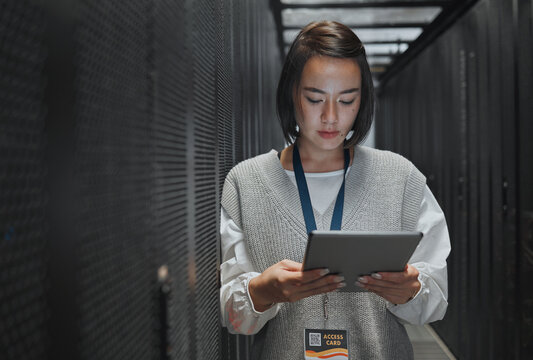 Tablet, server room and cloud computing with a programmer asian woman at work on a mainframe. Software, database and information technology with a female coder working alone on a cyber network