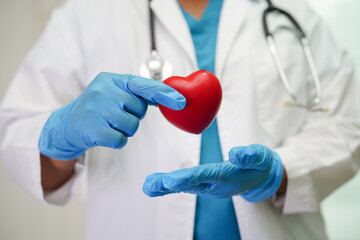 Asian woman doctor holding red heart for health in hospital.