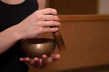 Female hands using singing bowl for relaxation and meditation.