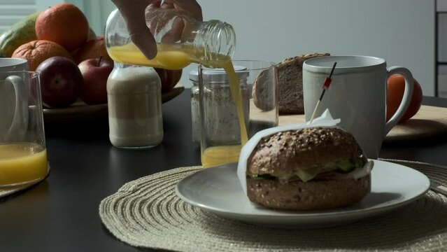 Nutritivo zumo de naranja es servido por una mujer en el desayuno con un bocadillo en un plato en primer plano 