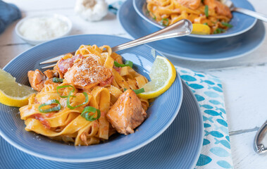 Pasta with salmon and creamy tomato sauce on blue plates