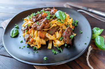 Pasta with beef ragout on a plate isolated on wooden background. Closeup