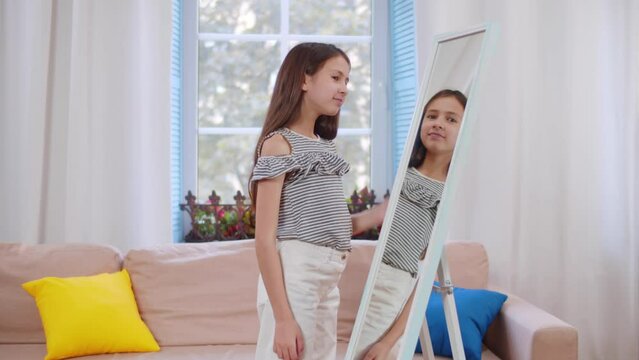 Portrait happy cute young teenage girl looking into mirror and smiling. Realtime