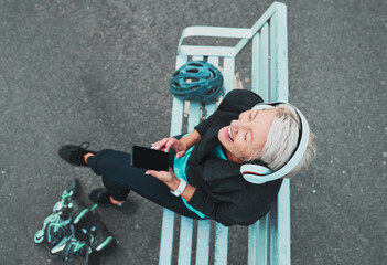 Phone, happy and woman roller skating with music for training, exercise and fun on a city bench....