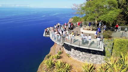 Tourists enjoy the viewpoint at Cabo Girao, along the Madeira coastline, Portugal. Aerial view from drone © jovannig