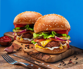 Tasty cheeseburgers on wooden tray close-up. Blue background.