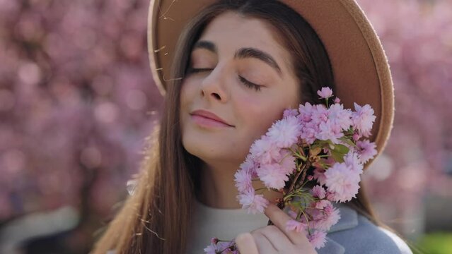 Beautiful Romantic Young Woman Poses Among Tender Pink Sakura Blossoms, Evoking the Inspiration of Spring and Summer for Perfume and Skincare Cosmetics Concept