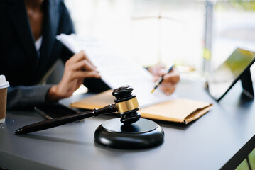 justice and law concept.law theme  wooden desk, books, balance. Male judge in a courtroom the gavel,working with digital tablet computer on table.