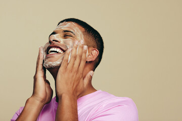 Starting his skincare routine with a refreshing face wash, man applies a facial cleanser - obrazy, fototapety, plakaty