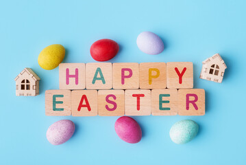 Decorative Easter eggs and wooden blocks with lettering Happy Easter on blue background. Easter holiday concept