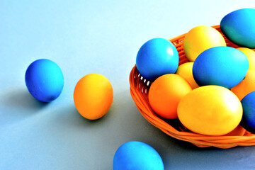 yellow and blue eggs in the basket isolated on blue background, close-up