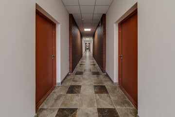 white empty long corridor with red brick walls for room office in interior of modern apartments, office or clinic