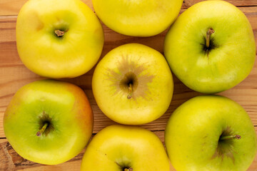 Several yellow organic apples on a wooden table, macro, top view.
