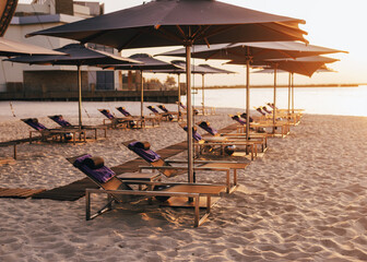 Rows of beach umbrellas and empty sunbeds on the beach, early morning. Travel and leisure concepts.