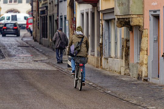Senior man with hat and walking stick at alley and male cyclist at the old town of Swiss City of Schaffhausen on a foggy winter day. Photo taken February 16th, 2023, Schaffhausen, Switzerland. - Powered by Adobe