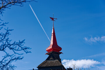 Red spire of residential house with wind vane at City of Schaffhausen on a sunny winter day. Photo taken February 16th, 2023, Schaffhausen, Switzerland.