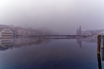 Naklejka premium Scenic view of Rhine River with car bridge an village Feuerthalen in the background on a foggy winter day. Photo take February 16th, 2023, Schaffhausen, Switzerland.