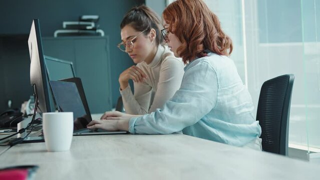 Computer programmers having a discussion while working on a code. Two business women collaborating on a software developing project in an office. Young female professionals working in a tech.