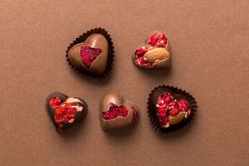 chocolate sweets in the form of a heart with fruits and nuts on a colored background. top view with space for text, holiday concept