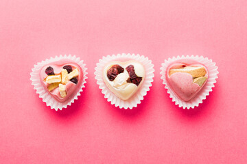 chocolate sweets in the form of a heart with fruits and nuts on a colored background. top view with space for text, holiday concept
