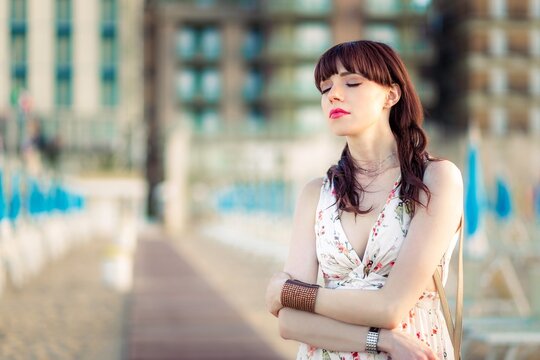 Portrait of a beautiful woman with her eyes closed standing on beach, Rimini, Emilia-Romagna, Italy