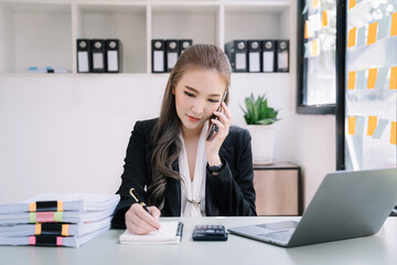 women talk mobile phones and take notes on their notebooks while working on laptop computers, online business, work from home, teleworking concept.