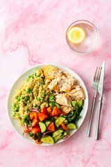 Healthy lunches, quinoa with green peas, with baked red fish salmon and fresh salad of tomato, cucumber and greens, top view