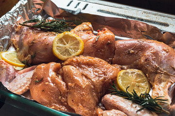 chicken pieces breast drumstick with rosemary and lemon,dish for eating,few pieces, delicious juicy, lies on a baking sheet for cooking in the oven of the stove in the kitchen. concept recipe chicken.