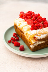Rich sweet pie with fresh fruits, decorated with red currants and raspberries, in a plate on a pink background