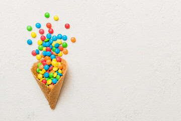 waffle cone full of assorted traditional candies falling out on colored background with copy space. Happy Holidays sale concept