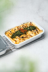 Tasty salmon mentai rice and wooden spoon on abstrack background with green leaves foreground