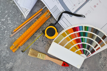 Architectural drawings with color guide, brushes, pencils, ruler on gray stone background. Top...