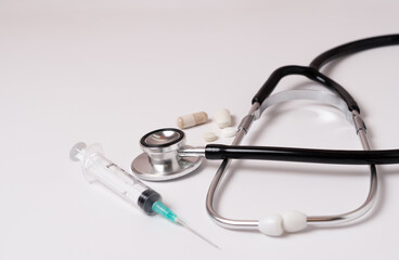 stethoscope, pills and syringe on a doctor's gown