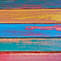 Wooden boards painted with a variety of bright colors. Bluish, yellow, orange and red horizontal pattern.