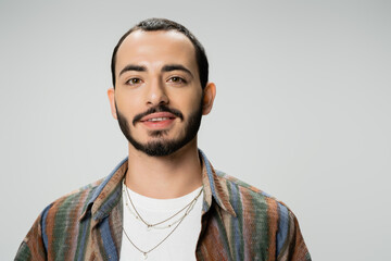 portrait of young bearded man in colorful shirt smiling at camera isolated on grey.