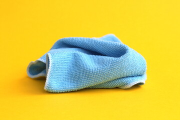 A blue rag for cleaning lies on a yellow background.	