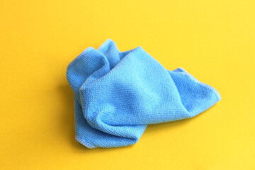 A blue rag for cleaning lies on a yellow background.