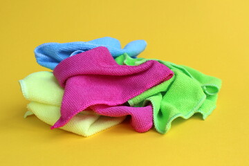 A bunch of different bright multi-colored napkins for cleaning lie on a yellow background.	