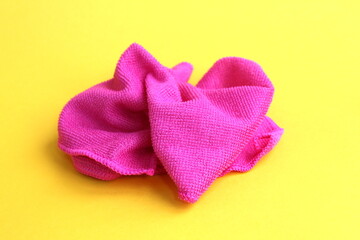 A pink rag for cleaning lies on a yellow background